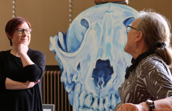 Teatterinjohtaja Iiristiina Varilo ja kuvataiteilija Arja Valkonen-Goldblatt keskustelevat teatterin aulassa. Taustalla sinisävyinen maalaus.